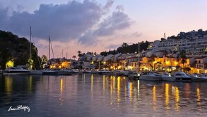 A marina with boats docked, waterfront buildings, and a sunset sky. - Excellent house facing the sea in urbanization with community pool (Almuñécar)