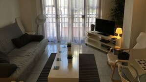 Ein Wohnzimmer mit Sofa, Couchtisch, Fernseher und Lampe.