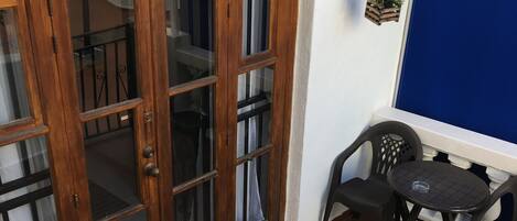 A wooden door with glass panels, a small round table with two chairs, a hanging plant, and a blue curtain.