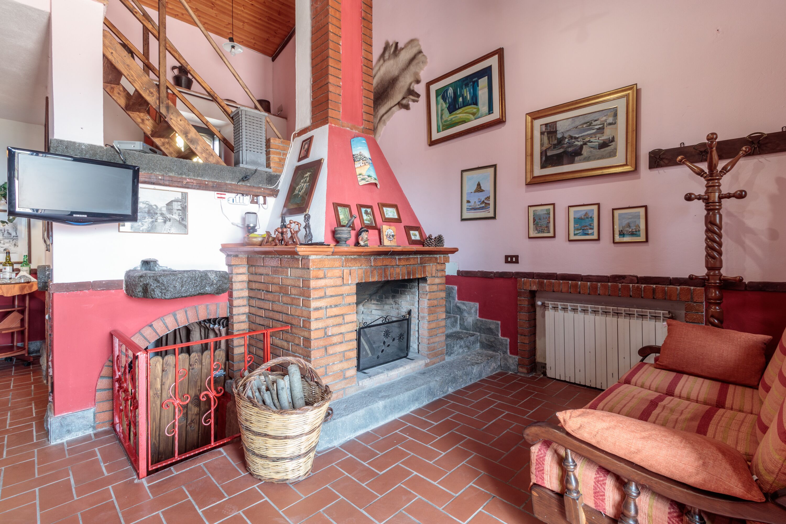 A cozy living room with a brick fireplace, a television, and a comfortable sofa.