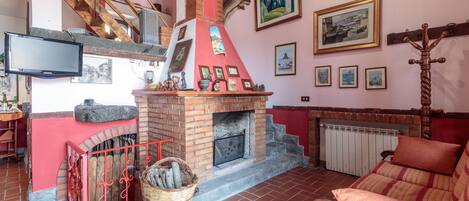 A cozy living room with a brick fireplace, a television, and a comfortable sofa.