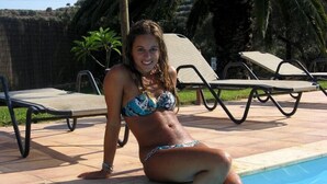 Un espace piscine avec des chaises longues et une personne assise au bord de la piscine.