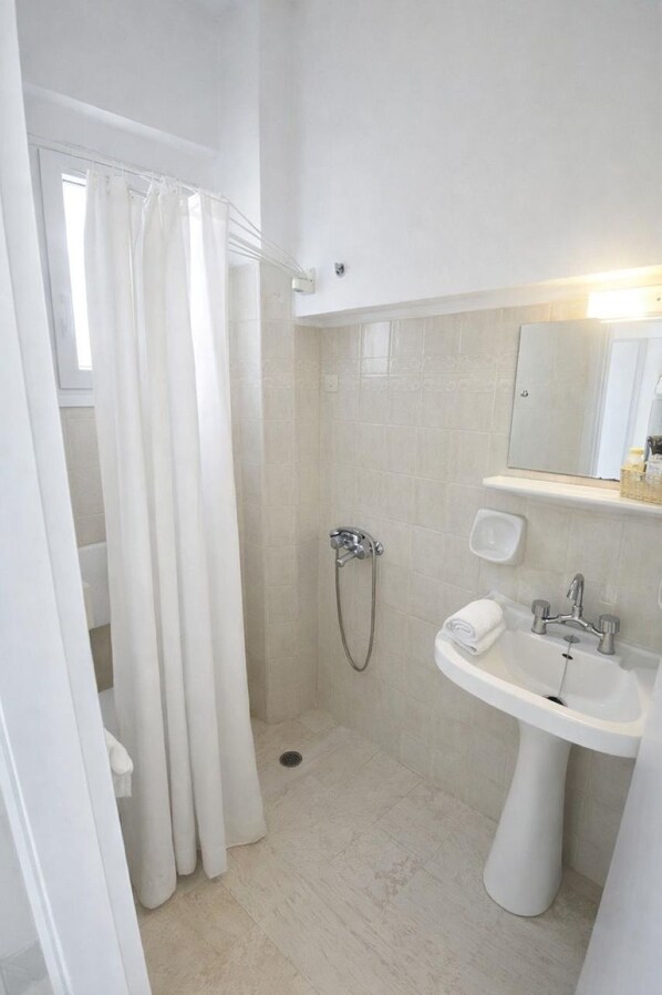 A bathroom with a shower, a sink, and a mirror.