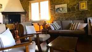 A cozy living room with stone walls, a fireplace, and a large window. There are two sofas and a wooden coffee table. - House / Villa - Monte San Savino (Monte San Savino)