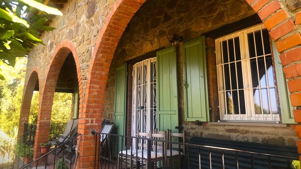A stone building with arched brick structures, green shutters, and a staircase leading to an upper level. - House / Villa - Monte San Savino (Monte San Savino)
