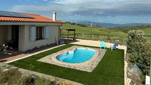 A house with a swimming pool, a patio, and a view of wind turbines in the distance. - Sos Giajos Rural house (Nulvi)