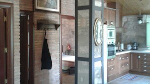 Una cocina con paredes de ladrillo visto, vigas de madera, una lámpara colgante y suelo de baldosas.