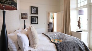 Une chambre d’hôtel avec un lit, une grande fenêtre et un tableau au mur.