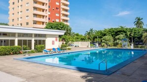 A swimming pool with lounge chairs and a building in the background. - Cosy & Stylish Studio at Turtle Beach Towers - Pool, Beach & Town Nearby  (Ocho Rios)