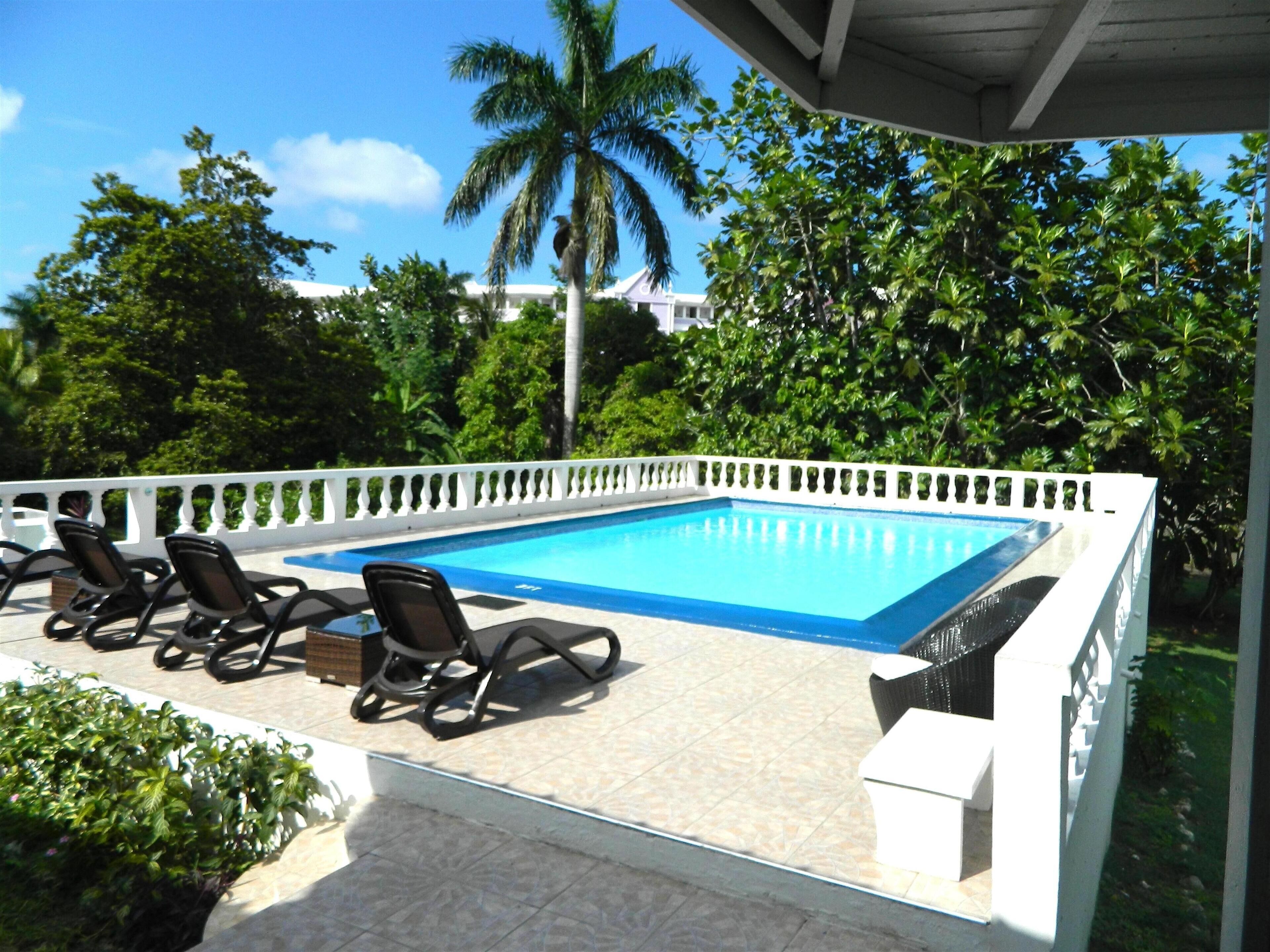 Uma área de piscina com espreguiçadeiras e um cercado branco.