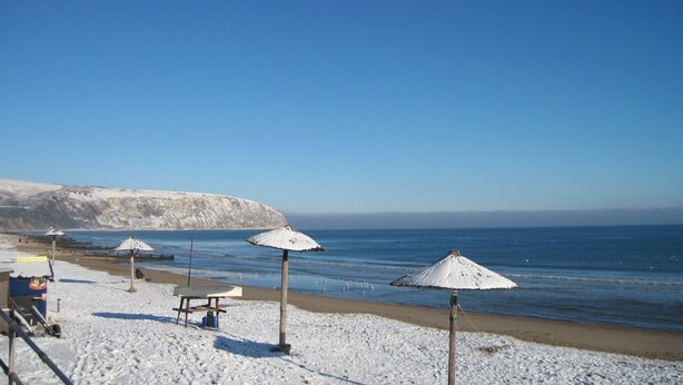 Ein Strand mit weißen Sonnenschirmen und blauem Himmel.