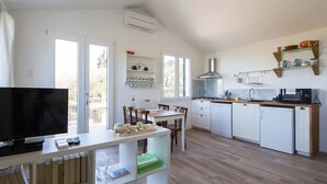 Una cocina moderna con armarios blancos, un microondas y una estufa. Hay un comedor con una mesa y sillas.