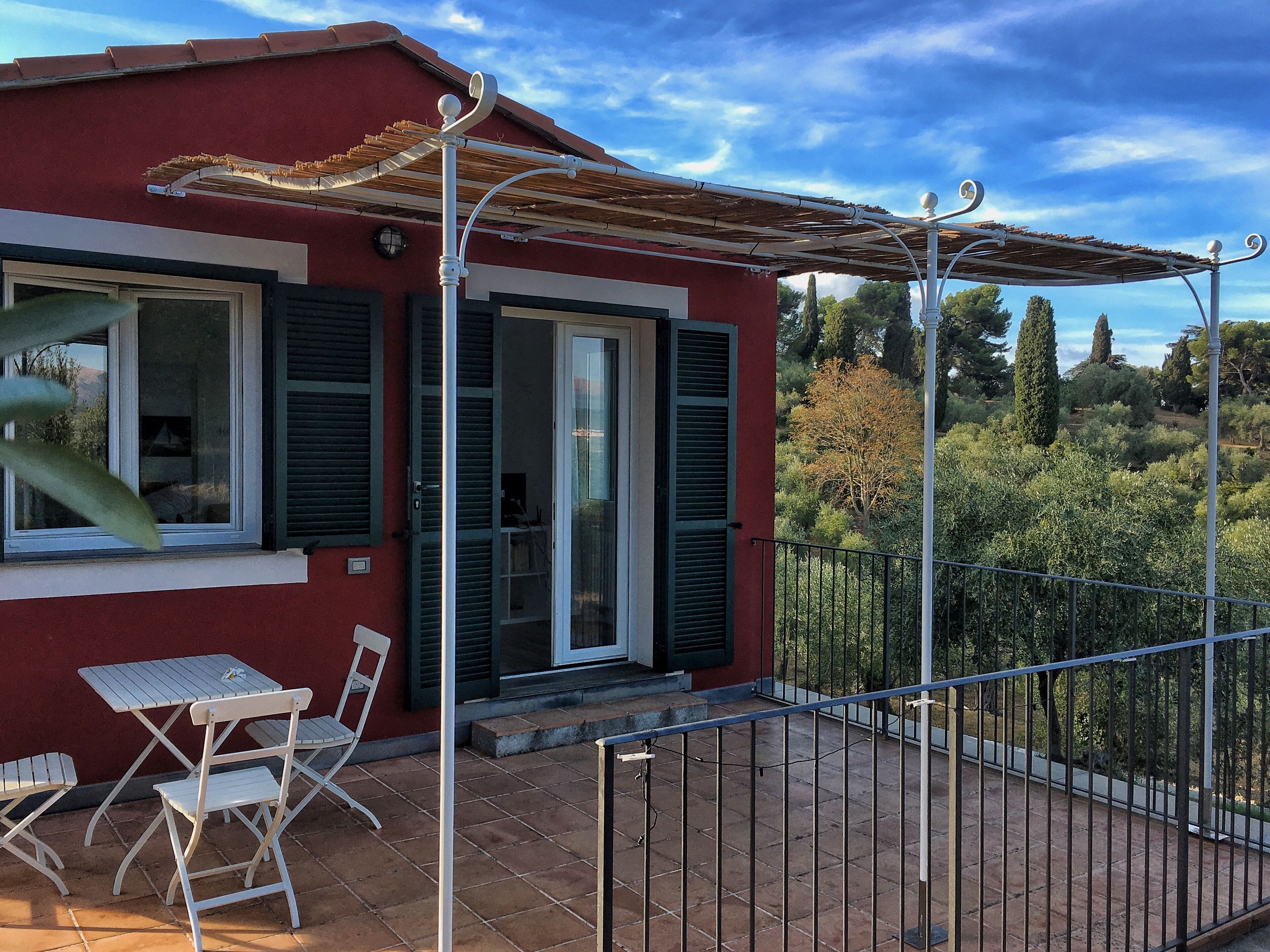 A red building with a balcony, a table, and two chairs.