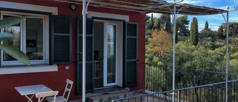 A red building with a balcony, a table, and two chairs.