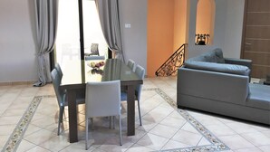 A living room with a sofa, a dining table with chairs, and a staircase.