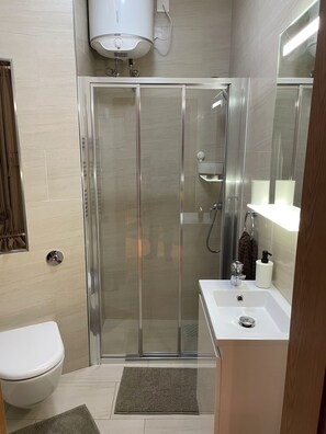 Une salle de bain moderne avec une douche à parois de verre, un lavabo blanc et des toilettes.
