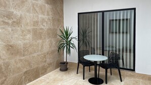 A small patio area with a table and chairs, a potted plant, and a sliding glass door.