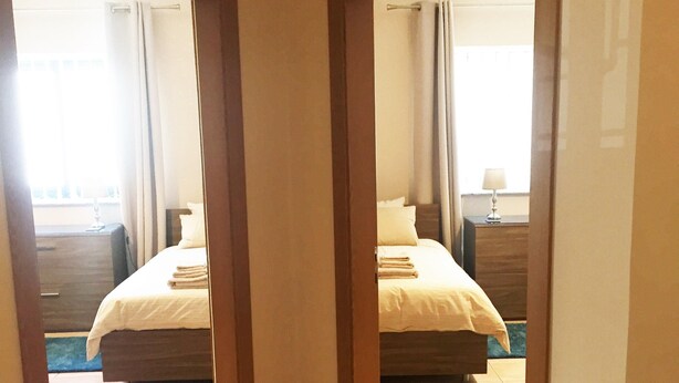 A hotel room with two beds, a wooden floor, and a view of the outside.