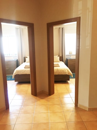 A hotel room with two beds, a wooden floor, and a view of the outside.