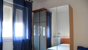 Een slaapkamer met een bed, een kledingkast en een stoel.