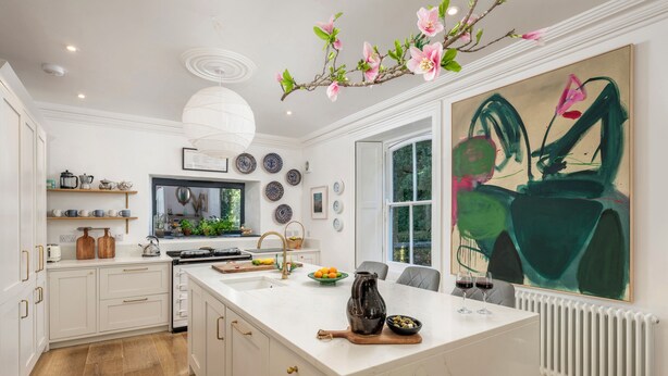 Een moderne keuken met witte kasten, een groot eiland en een eethoek met uitzicht op de tuin.