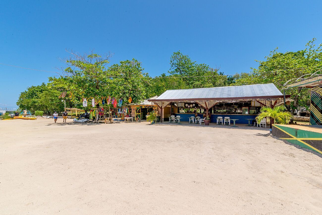 A beachside establishment with outdoor seating and a covered area.