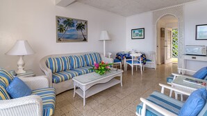 A living room with a sofa, coffee table, and chairs, a dining area with a table and chairs, and a kitchen area with a microwave. -  Waterfront ,  minutes from the beach, self catering, 24 hr security,            (Ocho Rios)