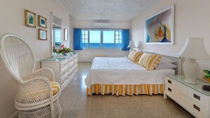A bedroom with a bed, a chair, a dresser, and a painting. -  Waterfront ,  minutes from the beach, self catering, 24 hr security,            (Ocho Rios)