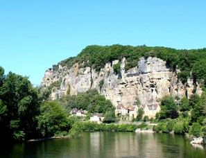 Ein Fluss mit einer felsigen Klippe und Häusern am Ufer.