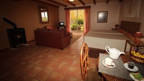 A cozy living room with a fireplace, a sofa, a dining table with a teapot and cups, and a view of the outdoors through a sliding door. - Quinta do Pântano is a calm and reserved place, with unique ambience and landscapes (Machico)