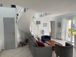 Una sala de estar moderna con techo curvo, un sofá, una mesa de centro y una escalera.