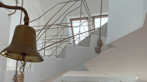 Un intérieur moderne avec un escalier, une cloche suspendue, un canapé, un téléviseur et une vue sur l’extérieur.