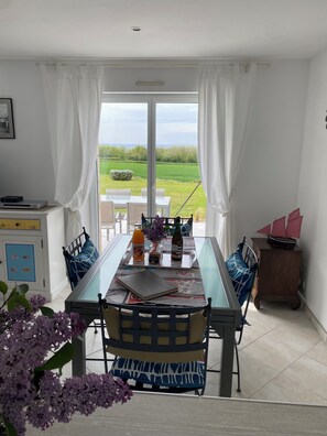 A dining area with a table, chairs, and a view of the outdoors. - 180° SEA VIEW, BEACH NEARBY FOR THIS SPACIOUS ARCHITECT-DESIGNED HOUSE (Primelin)