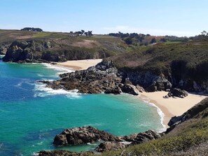 A coastal landscape with a sandy beach, rocky outcrops, and a clear blue sea. - 180° SEA VIEW, BEACH NEARBY FOR THIS SPACIOUS ARCHITECT-DESIGNED HOUSE (Primelin)