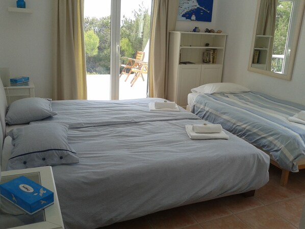 Une chambre d’hôtel avec deux lits, une table de chevet et une fenêtre donnant sur un paysage verdoyant.