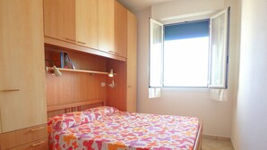A bedroom with a bed, wooden wardrobe, and a window with curtains.