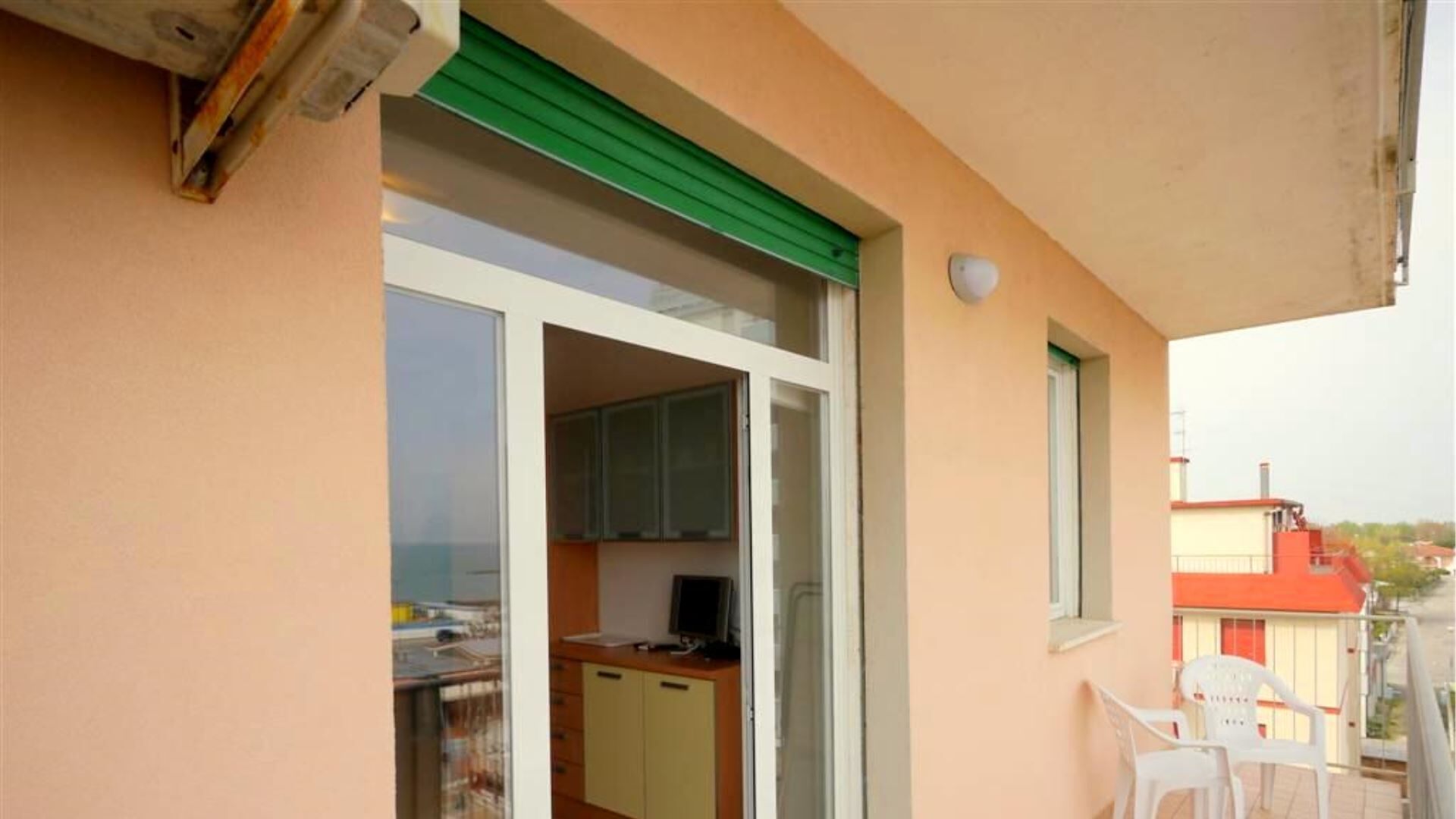 Un balcon avec une porte coulissante donnant sur un coin cuisine, une petite table et une chaise.