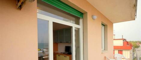 Un balcon avec une porte coulissante donnant sur un coin cuisine, une petite table et une chaise.
