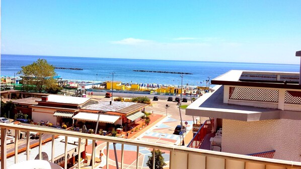 A coastal town with a view of the sea, buildings with balconies, and a paved area with shops. - Beautiful sea view, lovely two-room apartment air conditioned at the Lido di Pomposa (Comacchio)