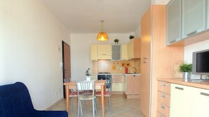 A compact kitchen with a dining area, a TV, and a hanging plant.