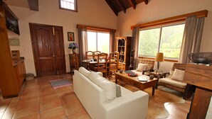 Un salón espacioso con un sofá blanco, una mesa de centro de madera y un comedor con mesa y sillas de madera.