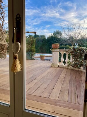 Une terrasse en bois offrant une vue sur un jardin et des arbres.