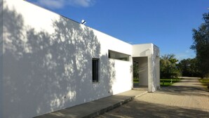 A modern building with a clean, white exterior, a small window, and a concrete pathway leading to a door.