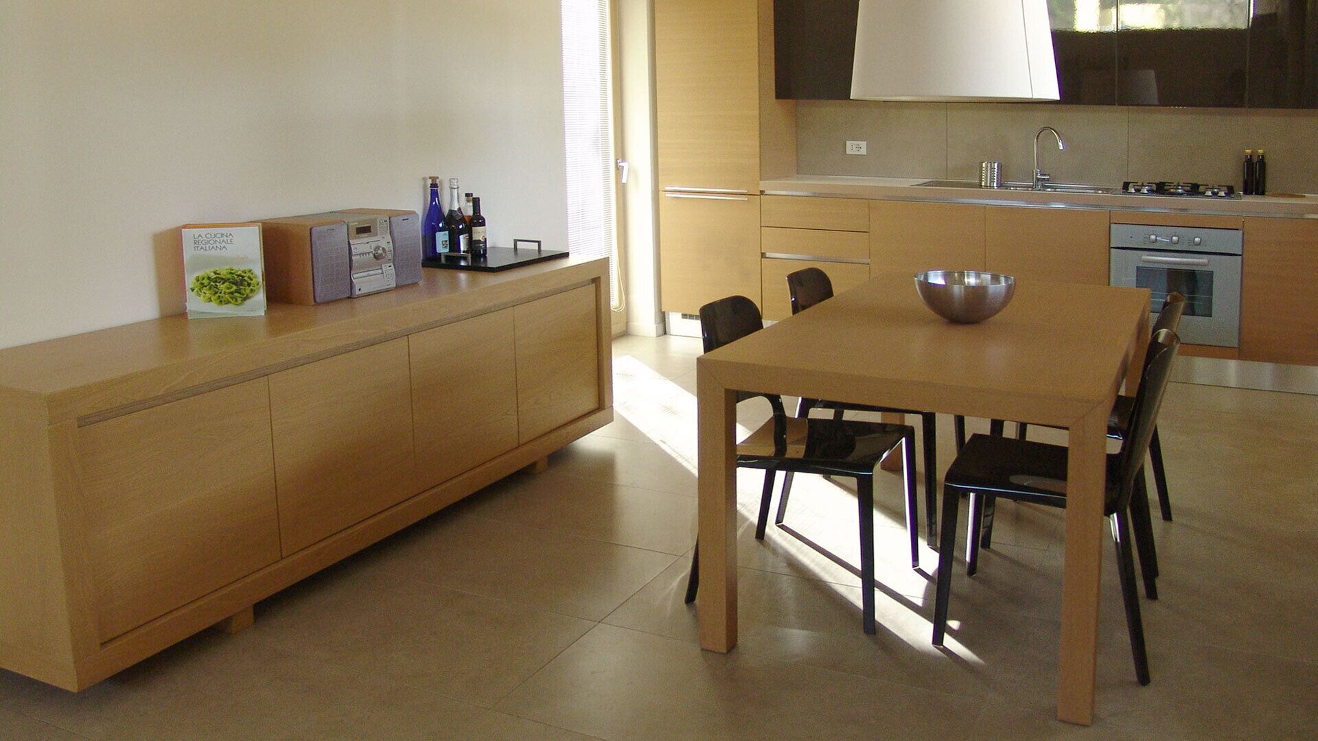 Une cuisine moderne avec une table à manger en bois, des chaises, un four encastré et un évier.