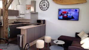 A modern kitchen with a microwave, a wooden surfboard, and a TV displaying a cooking show. - 2 ROOMS + MEZZANINE. All Biarritz on foot.  (Biarritz)