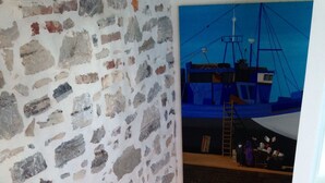 A staircase with a stone wall on one side and a painting of a ship on the other. - 2 ROOMS + MEZZANINE. All Biarritz on foot.  (Biarritz)