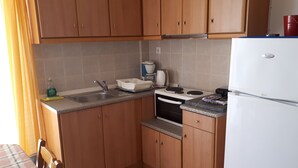 A kitchen with wooden cabinets, a sink, a stove, and a refrigerator. - Katerina Apartments ,( 1 ) One-Bedroom Apartment with Balcony (Kalamata)