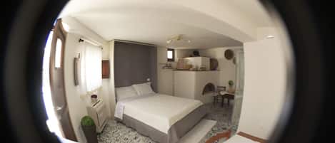 Un dormitorio con cama, mesita de noche y un pequeño espacio para escritorio.