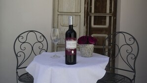 A table with a bottle of wine, two wine glasses, and a vase with flowers. - "Loft Costera" In the heart of the historic center of Orosei (Orosei, Nuoro)