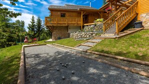 Eine Holzhütte mit Steinunterbau, einer Schotterterrasse und einer Holzterrasse.